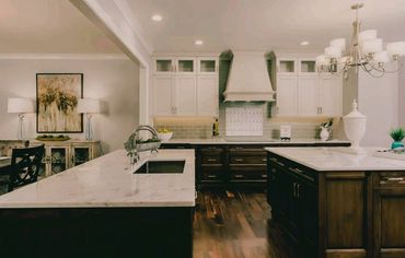 Modern kitchen with marble countertops, white cabinets, and elegant lighting.