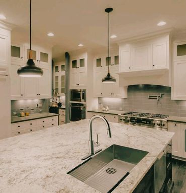 Modern kitchen with white cabinetry and marble island.