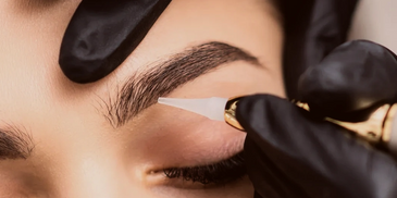 Performing a permanent makeup service, brows tattoo and eyebrows microblading, for woman.