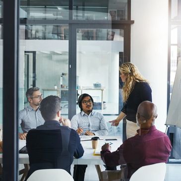 Team in a modern glass wall conference room with woman presenting, symbolizing nonprofit marketing.