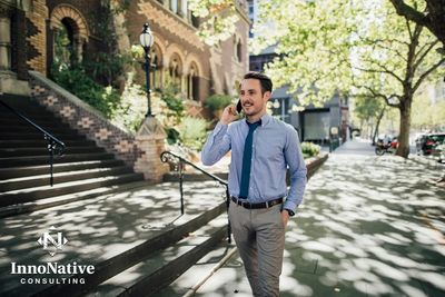 Professional Native-led consultant walking through urban neighborhood while on a phone call.