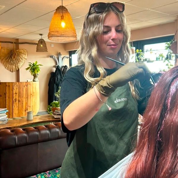 Hairdresser coloring a client's hair in a cozy salon.