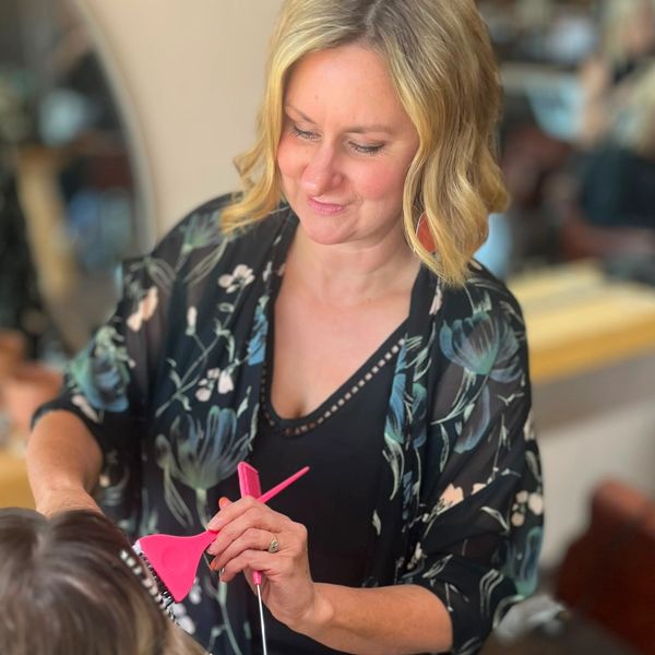 Woman dyeing hair with pink brush.