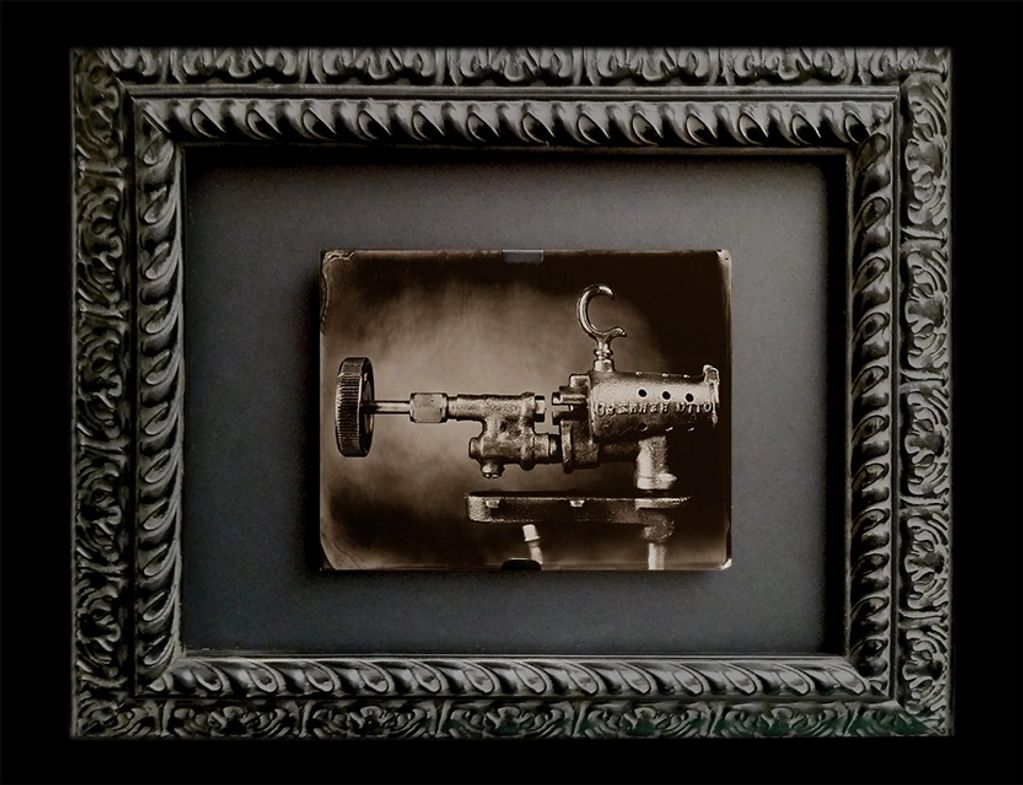 Antique mechanical device photographed and framed in ornate frame.