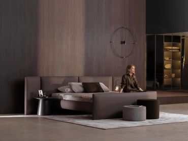 Modern bedroom with woman sitting on bed.