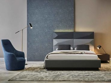 Modern bedroom with geometric headboard and blue chair.