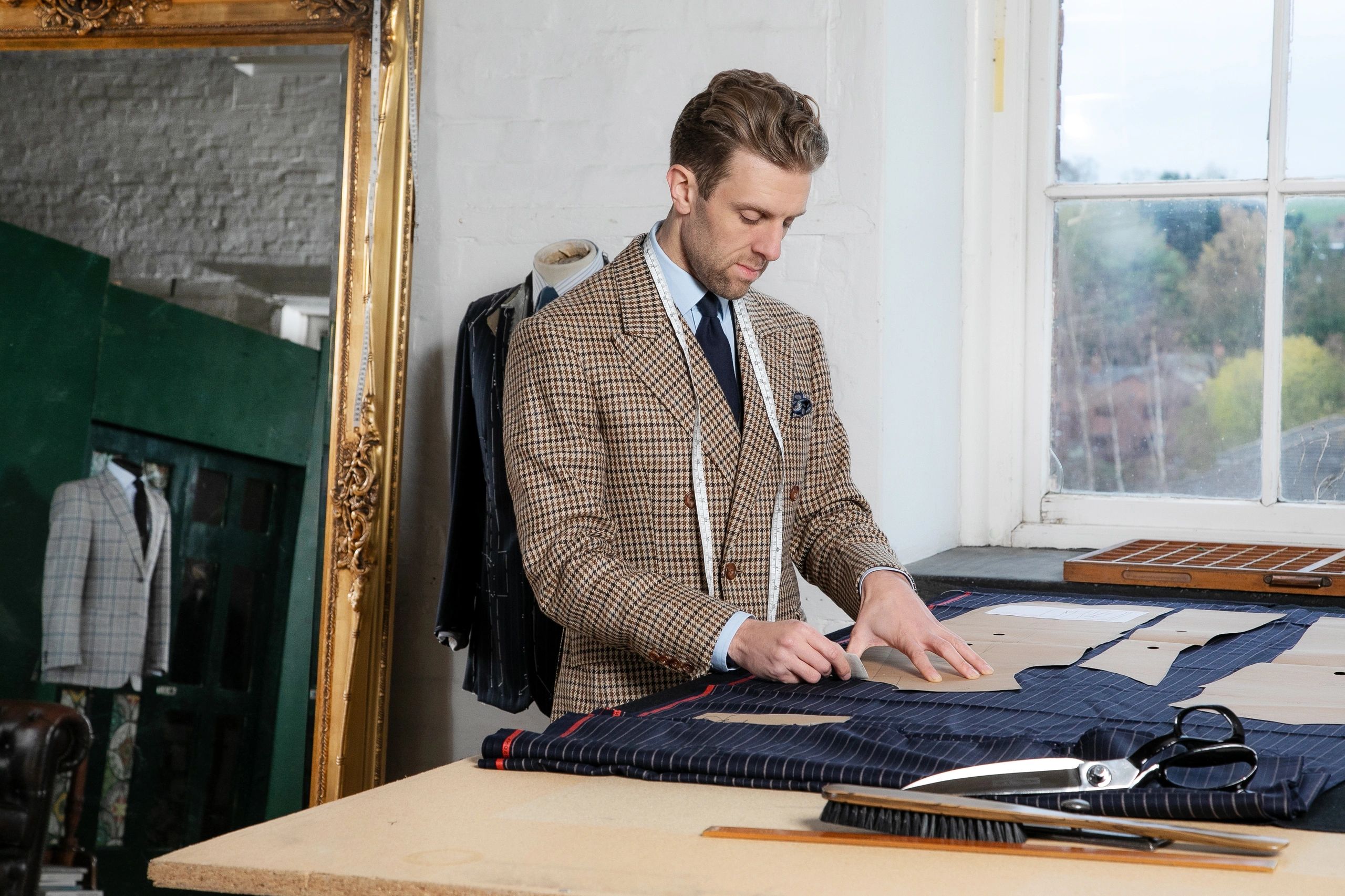 Nicholas striking a bespoke suit at his work board at the depot