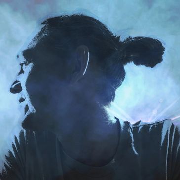 Profile of a man with a bun, laughing with blue smoky background.