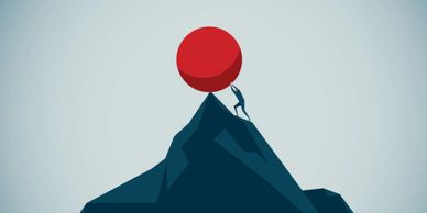 Man struggles to push a large red ball up a steep mountain.