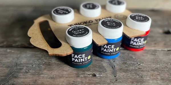 Small jars of colorful face paint on a wooden surface.