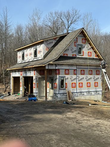 House under construction with workers and building materials around.