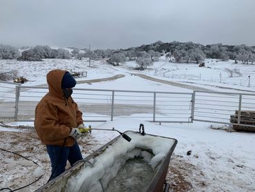 Ranchhand de-icing a frozen trough at Mountain House Ranch, Buffalo Gap, TX