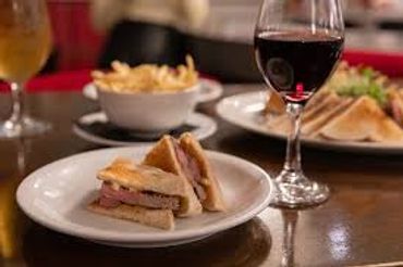 Club sandwich with fries and a glass of red wine on a Leadenhall restaurant table.