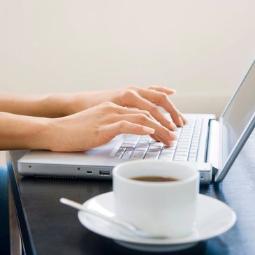 Typing on computer with coffee