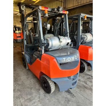Orange and gray Toyota forklift parked indoors on a concrete floor.