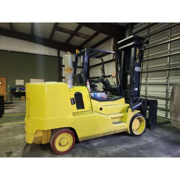 Yellow forklift parked inside a warehouse with safety equipment visible.
