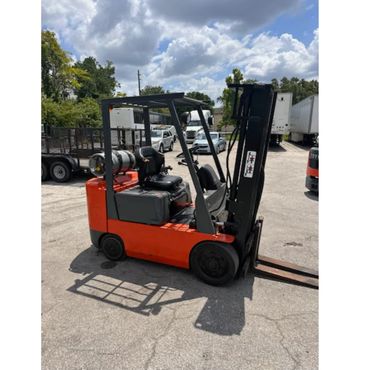 Orange and black forklift parked outside on a sunny day.