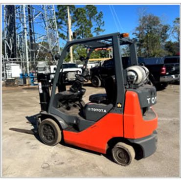 Toyota forklift parked outdoors with a bright orange body and black details.