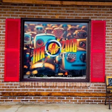 Window with red shutters displaying Ink-a-zoid Tattoos logo and robot artwork.
