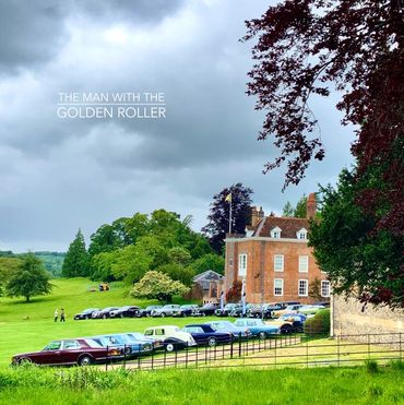 A photo of classic cars parked in front of a stately home.