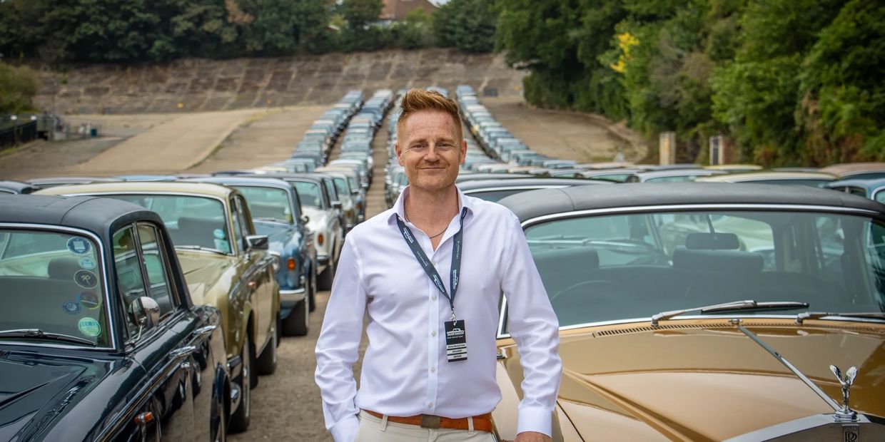 A man standing in front of a line of classic cars.