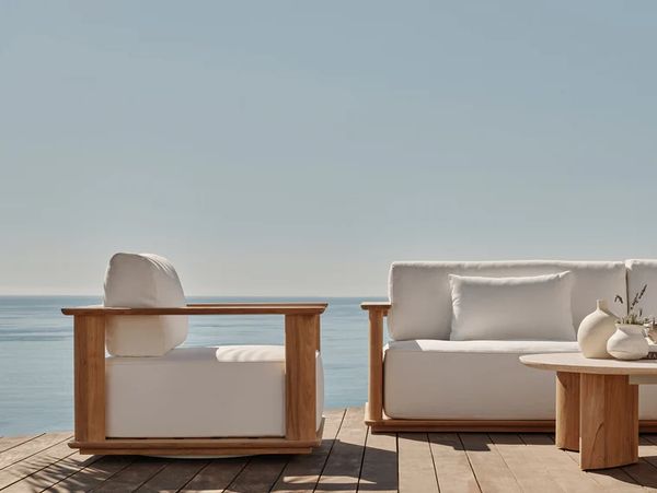 Minimalist wooden outdoor furniture by the sea on a sunny day.