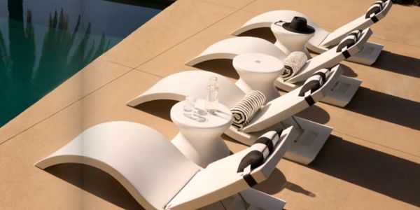 Modern white lounge chairs with striped cushions beside a pool under sunlight.