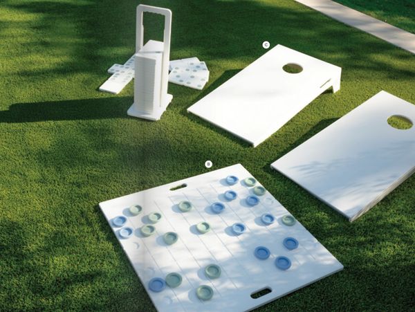 Outdoor lawn games including cornhole boards and a large checkers set on grass.