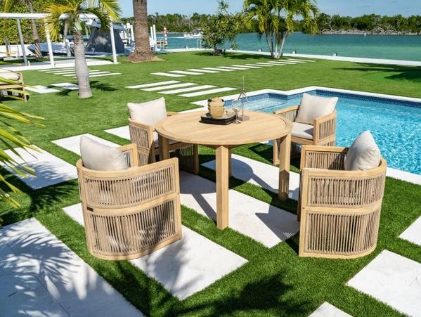 Outdoor wooden table and chairs set by a pool in a tropical setting.