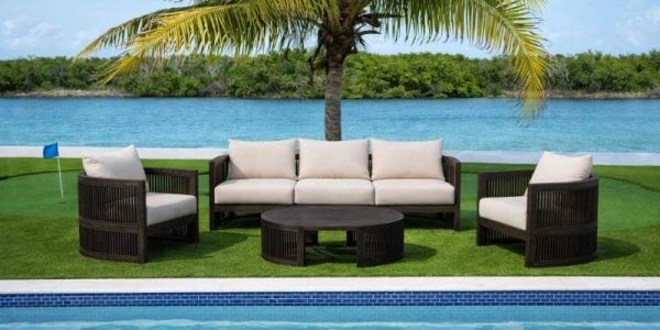 Outdoor seating set by a pool with a palm tree and water view.