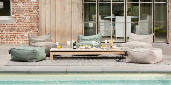 Outdoor seating area with bean bags and a low table by the pool.