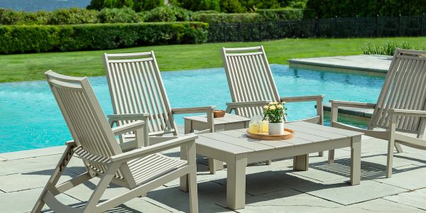 Outdoor patio furniture set by a pool on a sunny day.