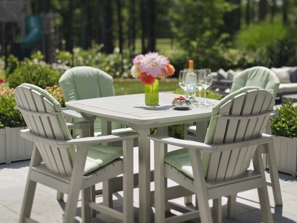 Outdoor patio table with cushioned chairs and floral centerpiece on a sunny day.