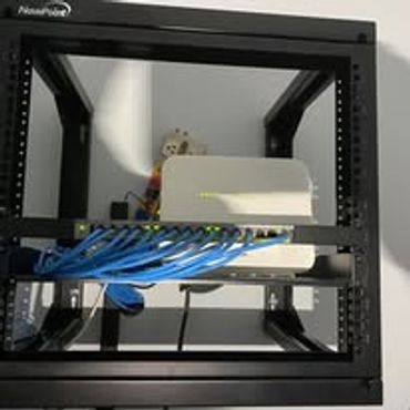 Network equipment with blue Ethernet cables mounted on a black rack.