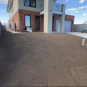 Newly constructed house with bare soil yard and brick facade.