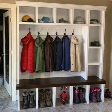 Organized coat rack with jackets, hats, boots, and umbrellas in a home entryway.