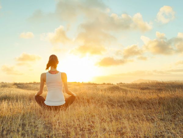 Woman focusing on herself in a field during sunset - Emotion Freedom Technique