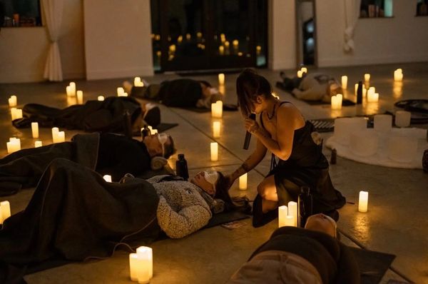 A group meditation session by candlelight with a woman leading.