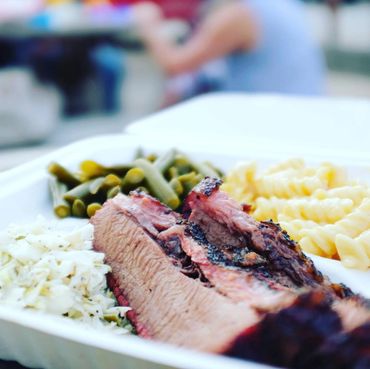 Brisket in a plate with green beans mac and cheese and slaw