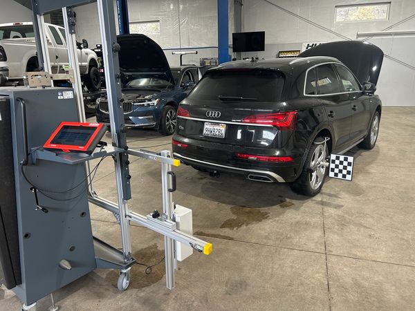 Audi Q5 undergoing wheel alignment in a workshop.
