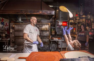 Chef throwing pizza dough in the air to son. Commercial photo shoot in Snohomish, WA