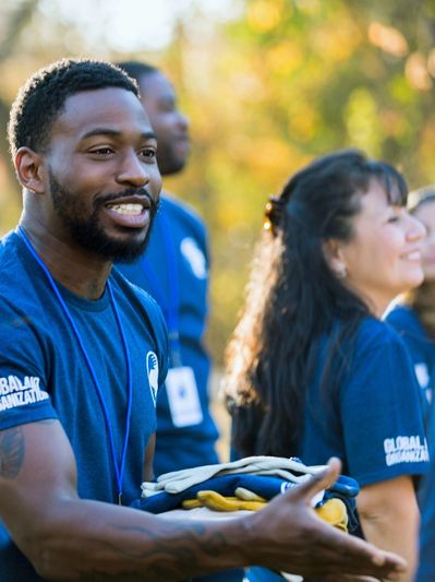 Image of a man extending his hand, wearing a t shirt that indicates he is part of a global organizat