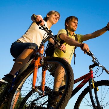 Young active couple on mountain bikes looking and pointing to the right 