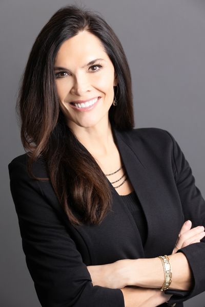 Confident woman with long dark hair smiling in professional attire.