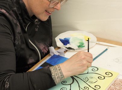 Young lady painting a tree onto a colourful canvas at a Saturday night painting class in Edinburgh.