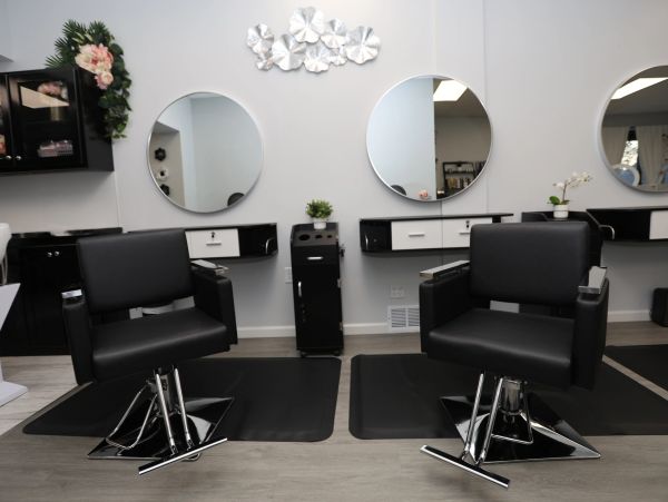 Modern salon with black chairs and round mirrors.