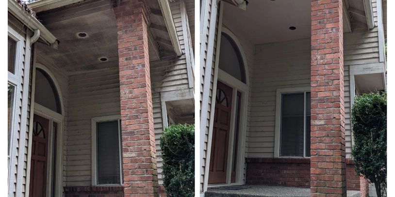 Front porch with brick column and a wooden door in a residential house. Mildew on the ceiling being cleaned up.