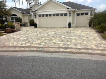 Elegant house with a large patterned driveway and three garage doors.