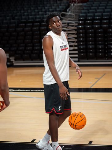 A basketball player in Cincinnati gear on the court holding a ball.