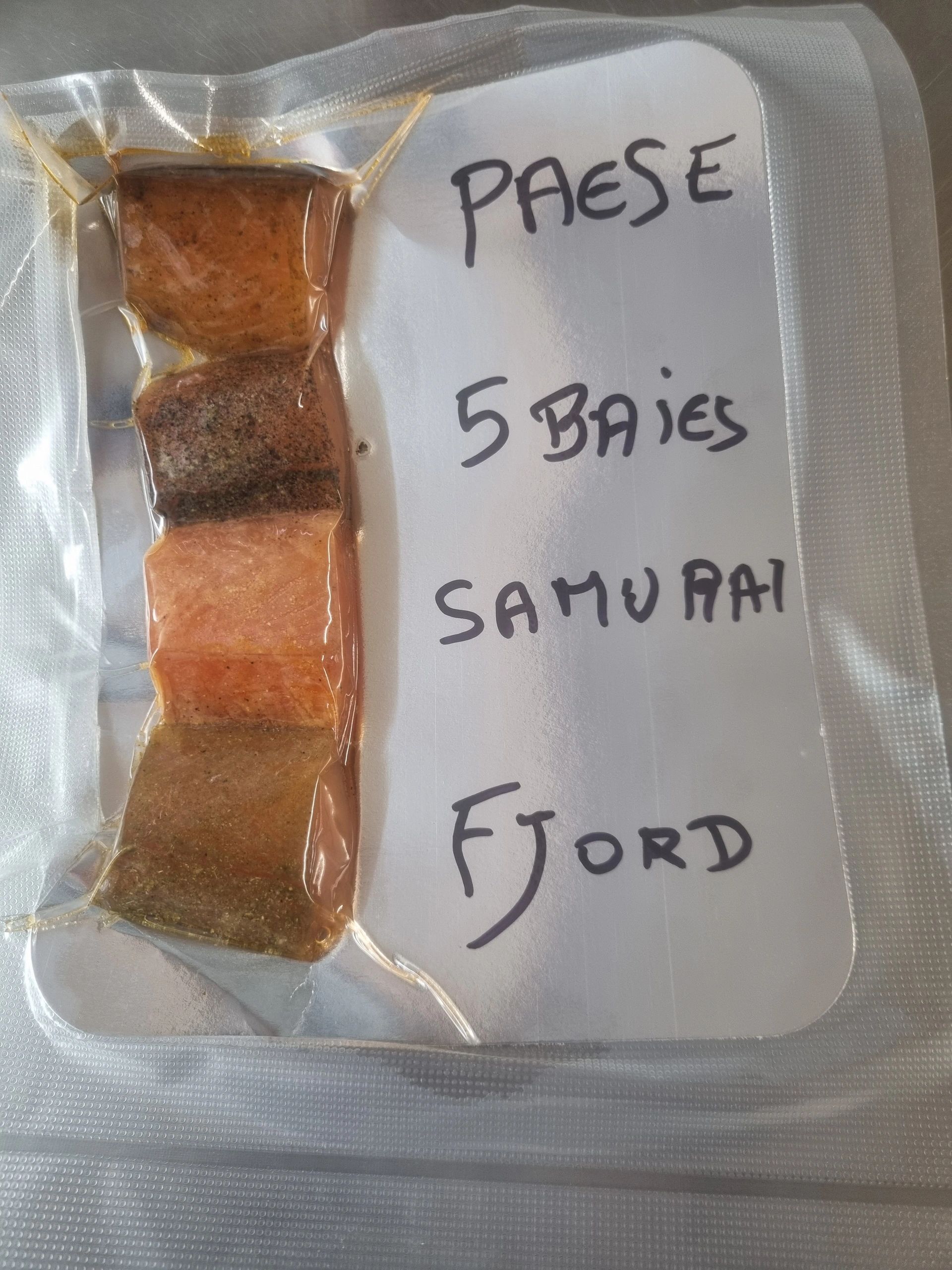 Vacuum-sealed fish fillets with handwritten labels including 'Paese', '5 Baies', 'Samurai', and 'Fjord'.